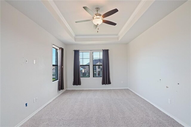 carpeted empty room featuring ceiling fan, ornamental molding, and a tray ceiling