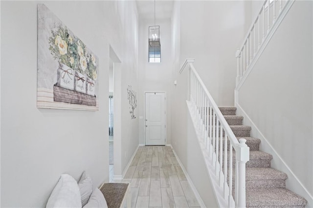 entrance foyer featuring hardwood / wood-style floors, a towering ceiling, and a notable chandelier