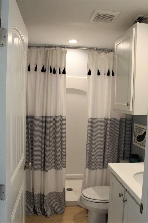 bathroom featuring vanity, hardwood / wood-style flooring, toilet, and curtained shower