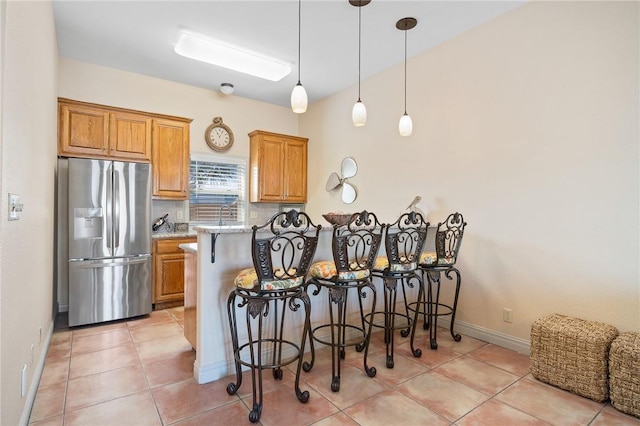 1114 Bay St, Aransas Pass, TX 78336 - kitchen featuring stainless steel fridge, a kitchen bar, a peninsula, and brown cabinets