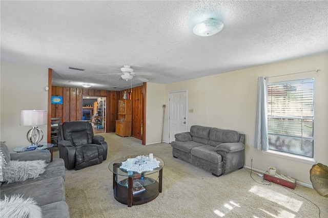 living area with baseboards, carpet flooring, a textured ceiling, and a ceiling fan