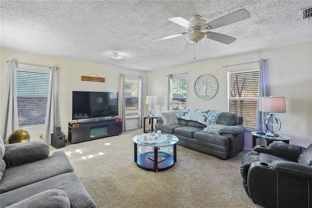 carpeted living area with visible vents, a textured ceiling, and ceiling fan