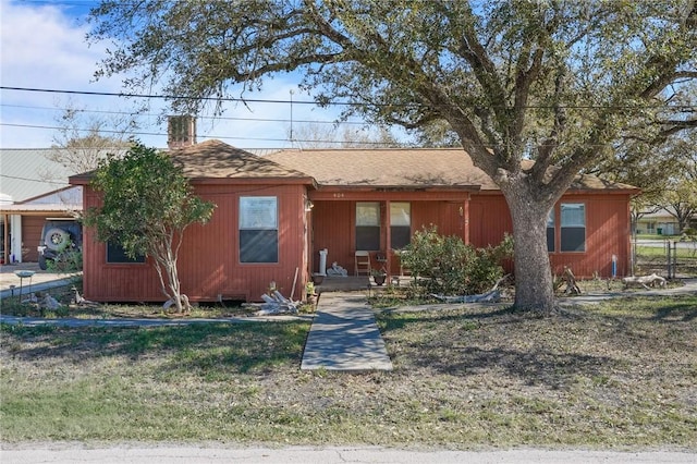 view of front facade featuring fence, a front yard, a chimney, and a shingled roof