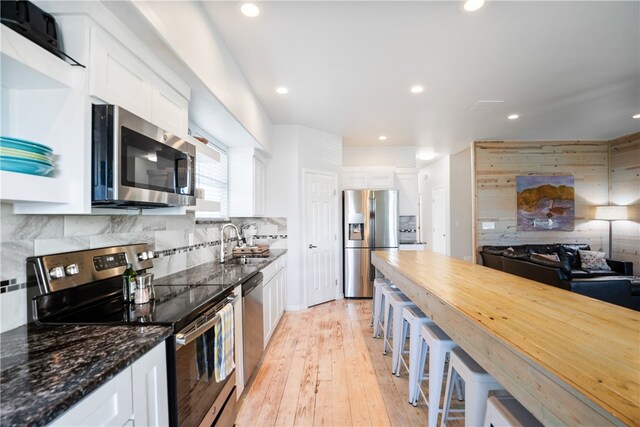 kitchen featuring white cabinets, light hardwood / wood-style flooring, sink, tasteful backsplash, and appliances with stainless steel finishes