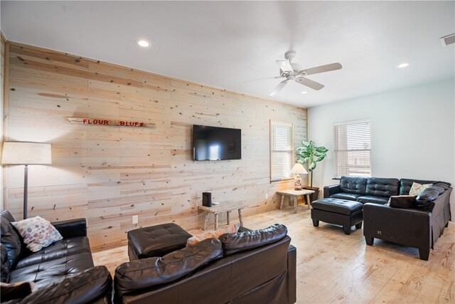 living room featuring ceiling fan, wooden walls, and light hardwood / wood-style flooring