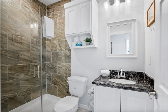 bathroom with walk in shower, vanity, and toilet