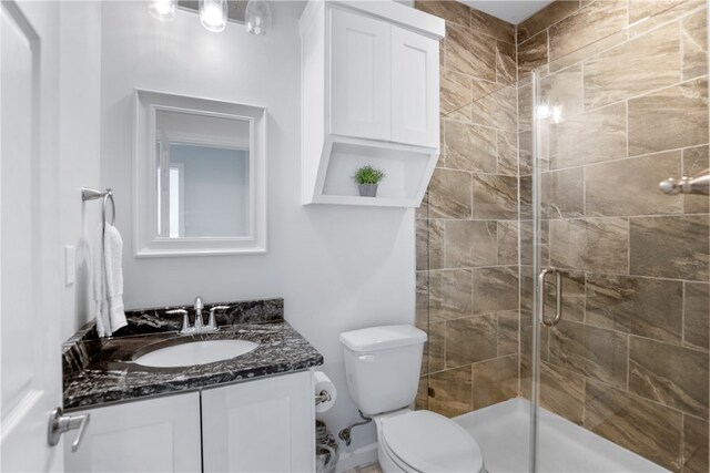 bathroom featuring an enclosed shower, vanity, and toilet