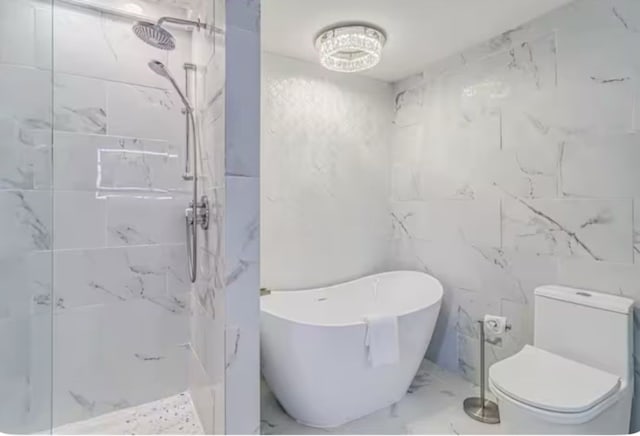 full bath with a freestanding tub, marble finish floor, a marble finish shower, and toilet