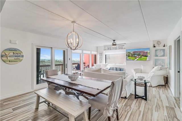 dining space with baseboards, light wood-style floors, and a notable chandelier