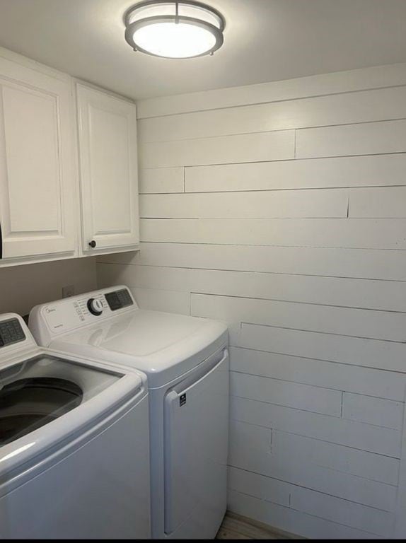 clothes washing area featuring separate washer and dryer and cabinet space