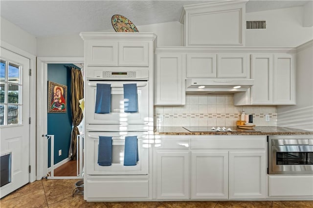 kitchen with visible vents, under cabinet range hood, white cabinets, black electric stovetop, and white double oven