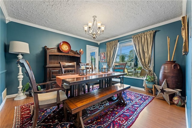 dining space with ornamental molding, wood finished floors, baseboards, and a chandelier