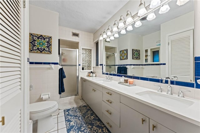 full bath featuring a sink, visible vents, toilet, and tile walls