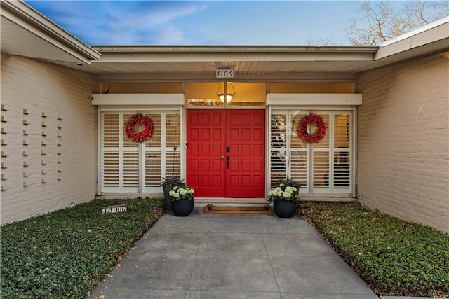 entrance to property with brick siding and a porch