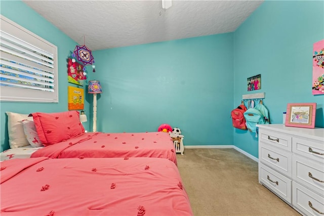 bedroom featuring baseboards, light carpet, a textured ceiling, and ceiling fan