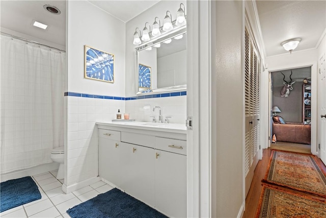 full bath featuring a wainscoted wall, toilet, tile walls, tile patterned flooring, and vanity