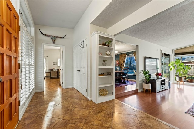 entryway with dark tile patterned floors, baseboards, and a textured ceiling