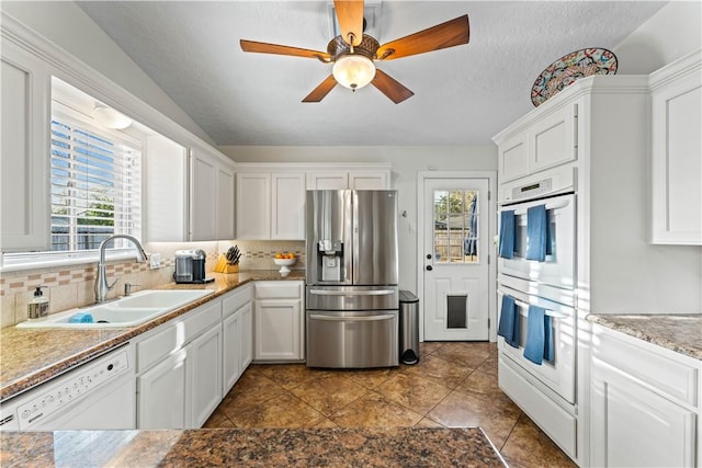 kitchen featuring a sink, white appliances, plenty of natural light, and white cabinetry