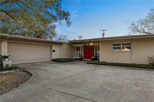 view of front of property with an attached garage, brick siding, and driveway