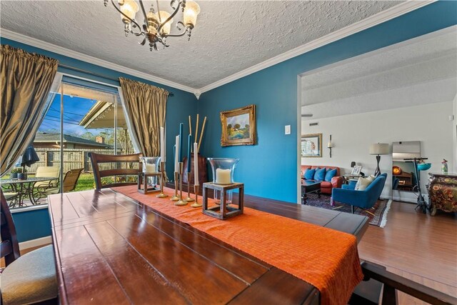 dining room featuring ornamental molding, a textured ceiling, an inviting chandelier, and wood finished floors