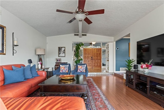 living area with a textured ceiling, lofted ceiling with beams, a ceiling fan, and wood finished floors