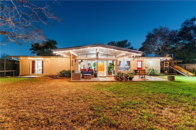 rear view of house with a playground, fence, a lawn, outdoor lounge area, and a patio