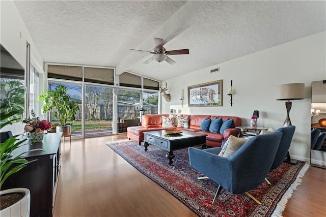 living area featuring visible vents, a ceiling fan, lofted ceiling with beams, a textured ceiling, and wood finished floors