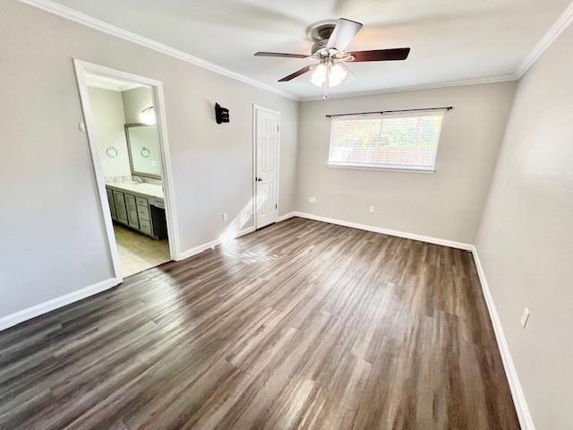 unfurnished bedroom with ceiling fan, dark hardwood / wood-style flooring, crown molding, and connected bathroom