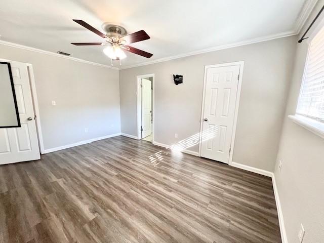 empty room with dark hardwood / wood-style floors, ceiling fan, and crown molding