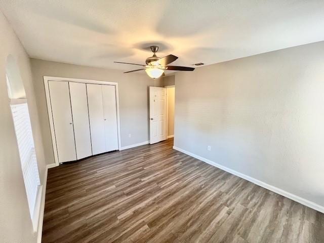 unfurnished bedroom featuring ceiling fan, dark hardwood / wood-style flooring, and a closet