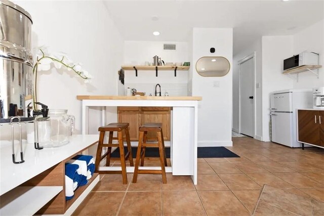 kitchen featuring light tile patterned flooring, sink, and white refrigerator