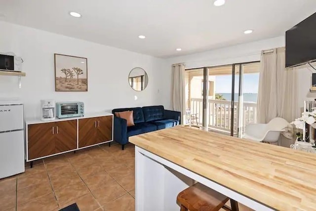 3938 Surfside Blvd Unit 1212, Corpus Christi, TX 78402 - kitchen with freestanding refrigerator, light tile patterned floors, recessed lighting, and brown cabinets