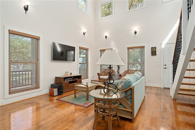 living room featuring a towering ceiling, light wood-type flooring, and a healthy amount of sunlight