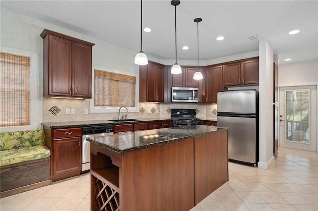 10 Old Cottage Beach Dr, Rockport, TX 78382 - kitchen featuring appliances with stainless steel finishes, a sink, light tile patterned flooring, a center island, and dark stone counters