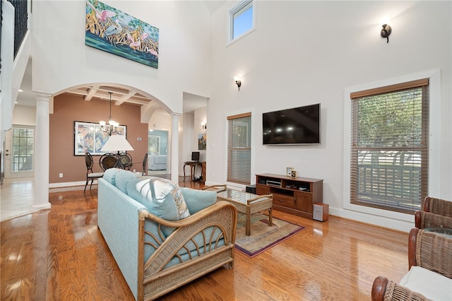 living room with light hardwood / wood-style floors, a high ceiling, plenty of natural light, and ornate columns