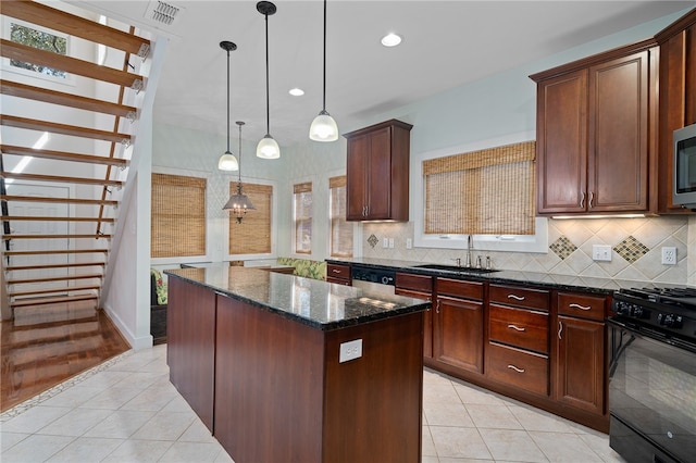 kitchen with stainless steel appliances, hanging light fixtures, sink, a kitchen island, and dark stone countertops