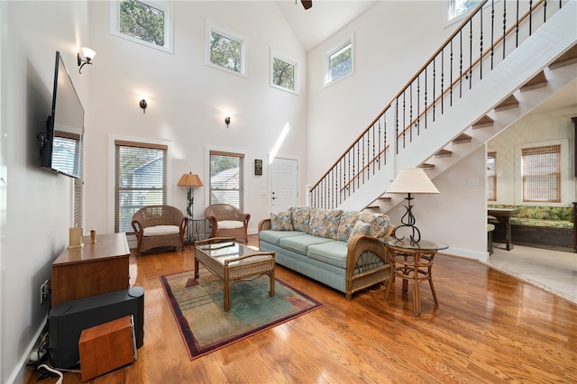 living room featuring light wood-type flooring, a towering ceiling, and plenty of natural light