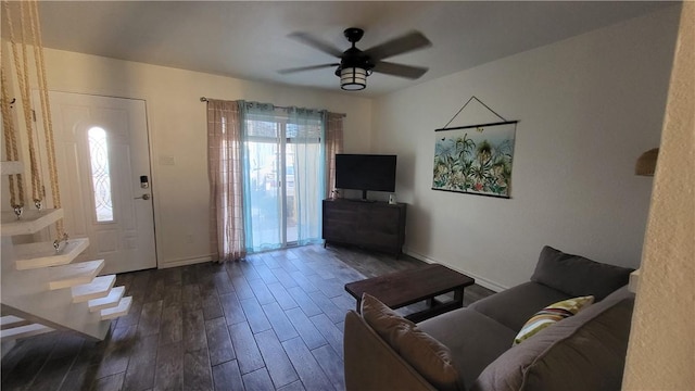 unfurnished living room with dark wood-style flooring, a ceiling fan, and baseboards