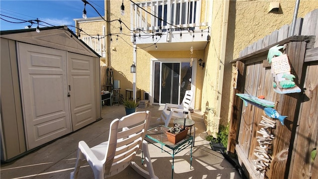 view of patio / terrace featuring a balcony, a storage unit, and an outbuilding