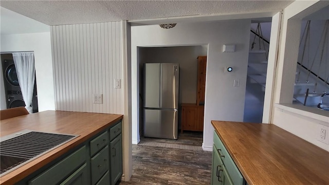 kitchen with green cabinets, butcher block countertops, stacked washer / dryer, and freestanding refrigerator