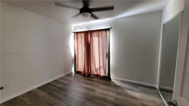 empty room featuring dark wood-type flooring, ceiling fan, and baseboards