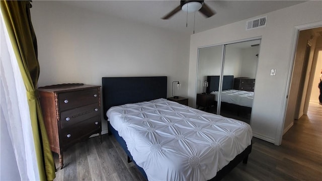 bedroom with a closet, wood finished floors, visible vents, and baseboards