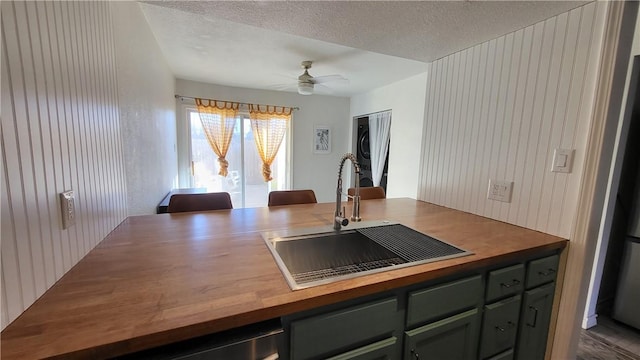 kitchen with butcher block countertops, a sink, a textured ceiling, and ceiling fan