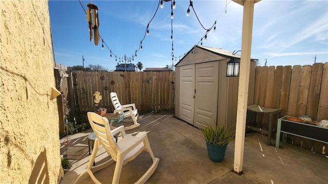 view of patio / terrace featuring a fenced backyard, a storage unit, and an outbuilding