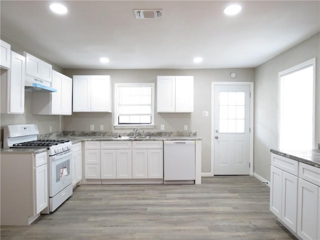 kitchen with light stone counters, light hardwood / wood-style floors, white appliances, and white cabinets