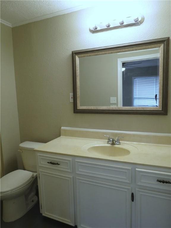 bathroom with toilet, vanity, a textured ceiling, and ornamental molding