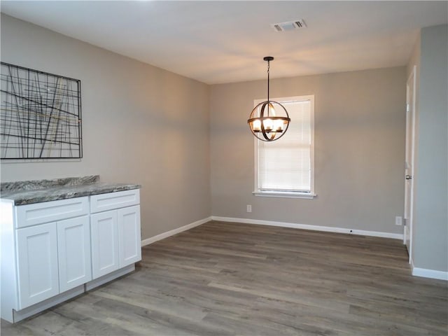 unfurnished dining area with hardwood / wood-style flooring and a chandelier