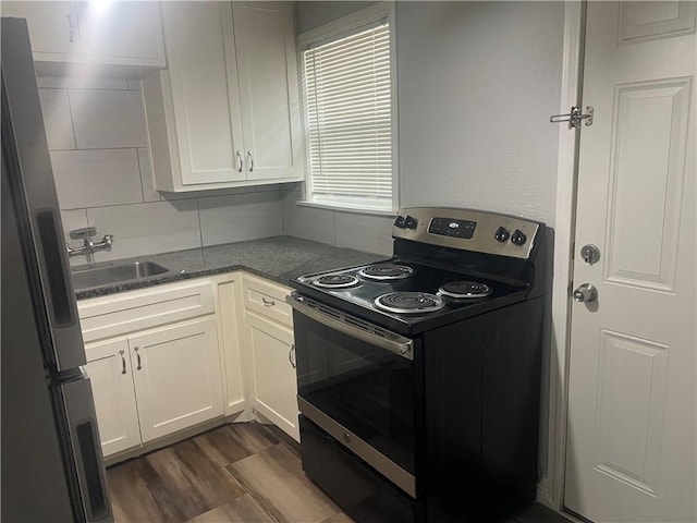 kitchen with electric range oven, sink, white cabinets, stainless steel fridge, and dark hardwood / wood-style flooring