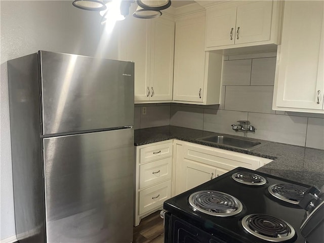 kitchen with sink, stainless steel refrigerator, black / electric stove, dark stone counters, and backsplash