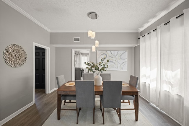 dining space with a textured ceiling, hardwood / wood-style flooring, and crown molding